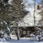 Ferienhaus Außenbereich im Winter: das verschneite Häusle hinter schützenden Bäumen