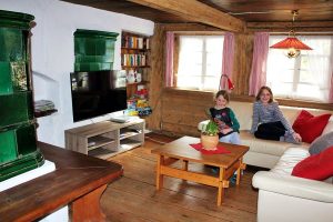 Ferienhaus Erdgeschoss: Kachelofen, Ledercouch und Flachbild-TV im Wohnzimmer
