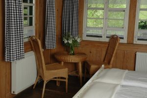 Ferienhaus Obergeschoss: Korbtisch mit Stühlen im weißen Schlafzimmer