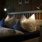 Ferienhaus Obergeschoss: elegantes Doppelbett im weißen Schlafzimmer