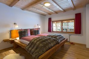 Ferienwohnung Altholzschlafzimmer: rustikales Altholz-Balkenbett mit stilechten Bezügen