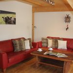 Ferienwohnung Innenräume: Wohnbereich mit gemütlichen Ledersofas, Flachbild-TV und Altholz-Couchtisch
