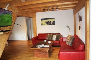 Ferienwohnung Innenräume: Wohnbereich mit Ledersofas, Altholz-Tisch und Flachbild-TV