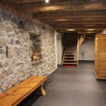 Der Flur zum Treppenhaus der Ferienwohnung: ausgestattet mit rustikaler Holzbank, traditionellem Bauernschrank und dezenter Deko